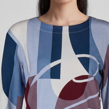 Load image into Gallery viewer, A close-up of a model wearing a long-sleeve top with an abstract geometric pattern in shades of blue, navy, burgundy, and white.
