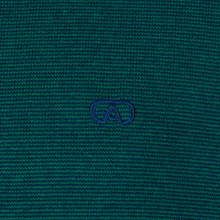 Load image into Gallery viewer, Close-up of a textured teal fabric with a logo in the center.
