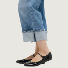 Load image into Gallery viewer, Person wearing black flat shoes and light blue jeans with a white background

