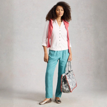 Load image into Gallery viewer, Woman wearing a white shirt, pink cardigan, and blue pants, holding a patterned bag against a plain background
