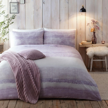 Load image into Gallery viewer, A bed dressed in a soft lavender and white striped bedding set with matching pillows and a ribbed lavender throw blanket, styled in a rustic bedroom with wood paneling, a bedside table, and a lamp.
