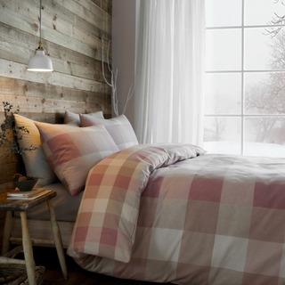 Bedroom with checkered bedding and wooden wall.