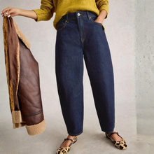 Load image into Gallery viewer, Person wearing blue jeans and a yellow sweater, holding a brown leather jacket.
