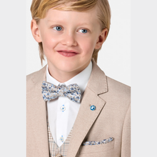 Load image into Gallery viewer, Young boy wearing a beige suit with a floral bow tie and pocket square on a light gray background
