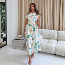 Load image into Gallery viewer, Woman in a floral dress standing in a modern living room.
