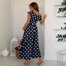 Load image into Gallery viewer, Woman wearing a navy blue dress with white polka dots in a room with decorative items.
