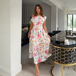 Woman in a floral dress standing in a modern kitchen.