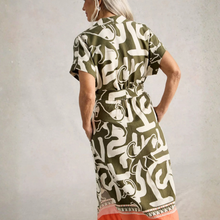 Load image into Gallery viewer, Woman wearing a green dress with white abstract patterns against a plain background
