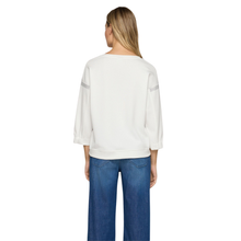 Load image into Gallery viewer, Woman wearing a white sweater and blue jeans on a white background
