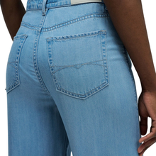 Load image into Gallery viewer, Close-up of blue jeans with a focus on the back pocket.
