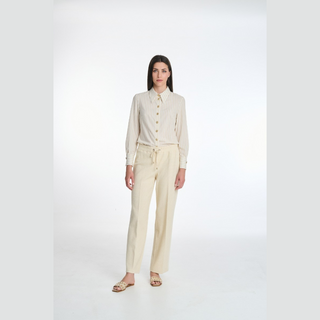 Woman wearing a beige shirt and pants on a white background