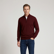 Load image into Gallery viewer, A man wearing a burgundy quarter-zip mock neck sweater over a white undershirt and blue jeans, standing against a light gray studio background.
