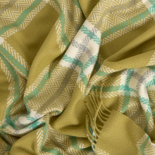 Load image into Gallery viewer, A close-up of a woven scarf or throw blanket with a plaid pattern in olive green, white, and mint green, featuring fringed edges.

