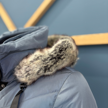 Load image into Gallery viewer, Close-up of a blue jacket with a fur-lined hood against a blurred background
