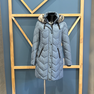 Gray quilted coat with fur-lined hood on a stand against a geometric-patterned wall.