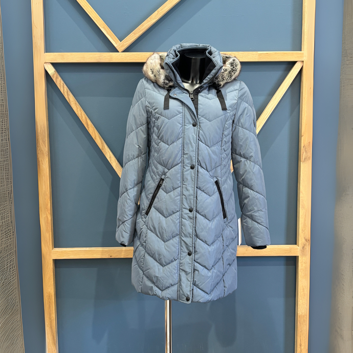 Gray quilted coat with fur-lined hood on a stand against a geometric-patterned wall.