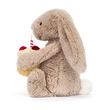 Load image into Gallery viewer, Plush bunny holding a small cake with a candle on a white background
