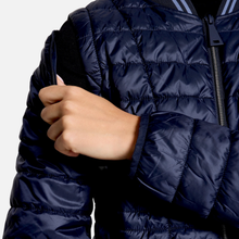 Load image into Gallery viewer, Close-up of a person wearing a navy blue quilted puffer jacket, showing the hand adjusting the zipper or sleeve.
