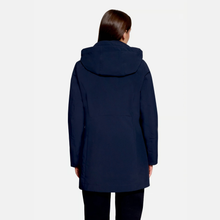 Load image into Gallery viewer, A woman viewed from the back wearing a dark navy hooded coat and black pants against a light gray studio background.
