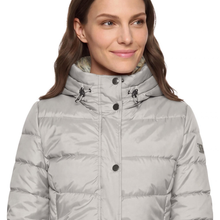 Load image into Gallery viewer, A woman wearing a light gray puffer jacket with a high collar and black snap buttons, shown from the chest up against a plain white background.
