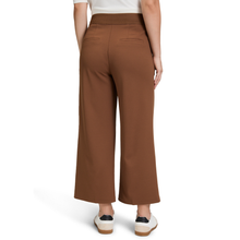 Load image into Gallery viewer, A model shown from the back wearing high-waisted, wide-leg cropped pants in a warm brown color, paired with a white top and white sneakers with black accents, on a solid white background.
