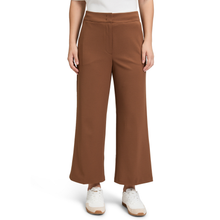 Load image into Gallery viewer, A model wearing a pair of wide-leg cropped pants in a warm brown color, paired with a white top and white sneakers, shown against a plain white background.
