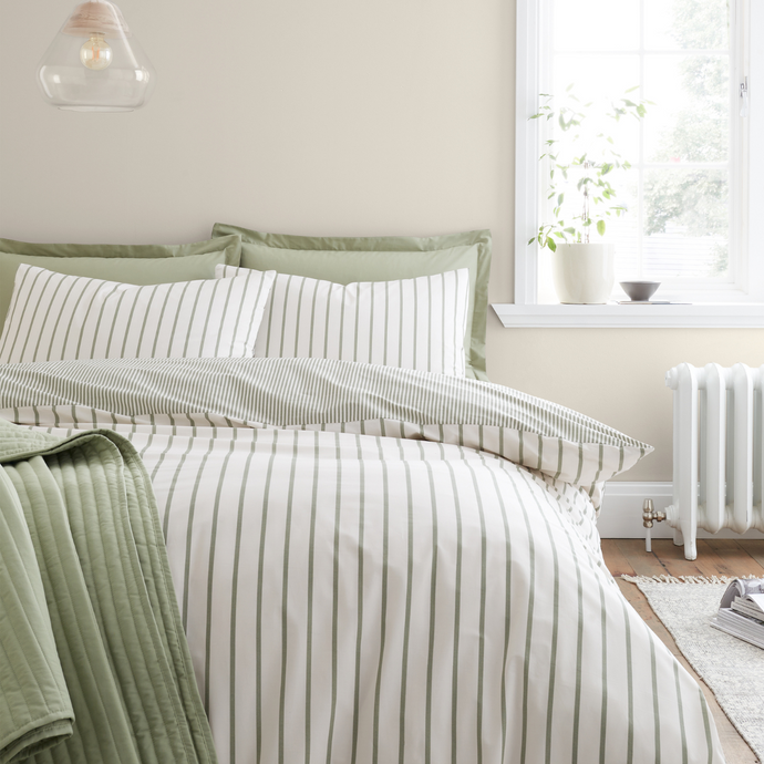 Bed with green and white striped bedding in a bright bedroom.