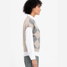 Load image into Gallery viewer, A woman shown in side profile wearing a beige and gray argyle knit sweater vest over a white collared shirt, against a plain light background.
