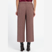 Load image into Gallery viewer, A model is shown from the back wearing high-waisted, wide-leg cropped trousers in a textured brown and beige tweed pattern, paired with black ankle boots.
