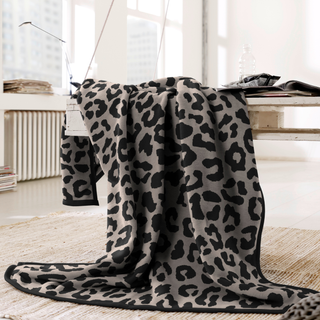 Leopard print blanket draped over a white surface in a bright room.