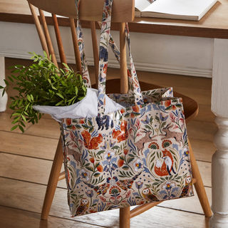 Floral-patterned tote bag with plants on a wooden chair indoors