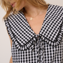 Load image into Gallery viewer, Black and white checkered blouse with ruffled collar and cuffs on a plain background

