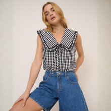 Load image into Gallery viewer, Woman wearing a black and white checkered top and blue denim shorts on a plain background
