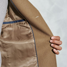 Load image into Gallery viewer, Close-up of a brown coat with a hand touching the fabric on a light gray background
