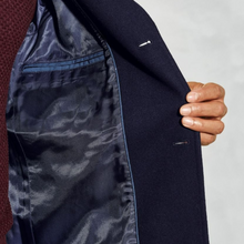 Load image into Gallery viewer, Navy suit jacket with a subtle pattern on the lapel held by a hand against a neutral background
