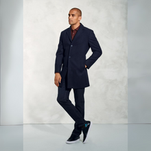Load image into Gallery viewer, Man wearing a navy overcoat and dark pants against a light gray background
