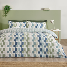 Load image into Gallery viewer, Bed with geometric patterned bedding in a room with a green headboard and small table.
