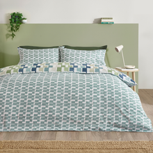 Load image into Gallery viewer, Bed with geometric patterned bedding in a room with a green headboard and lamp.
