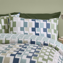 Load image into Gallery viewer, Geometric patterned bedding set with green, blue, and white colors on a bed.
