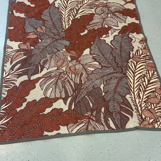 Floral patterned Throw with brown and beige colors on a light gray floor.