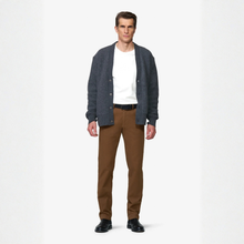 Load image into Gallery viewer, A man modeling a dark gray knit cardigan over a white t-shirt, paired with brown trousers and black shoes, against a plain white studio background.
