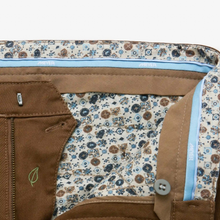 Load image into Gallery viewer, Close-up of the interior waistband and pocket area of a pair of brown pants, showing a floral lining pattern in beige, blue, and brown, a light blue inner band, and a brown zipper pocket.
