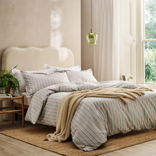 Bedroom with striped bedding and a green pendant light.