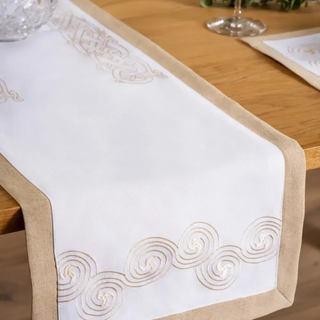 White table runner with gold embroidery on a wooden table