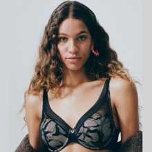 Load image into Gallery viewer, A model wearing a jacket shrugged off the shoulders while displaying the Chantelle True Lace Plunge Spacer Bra.
