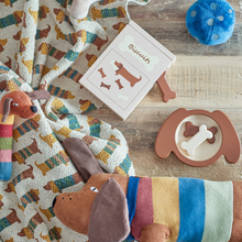 Load image into Gallery viewer, Dog-themed items including a blanket, toys, and a box on a wooden surface.
