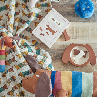 Dog-themed items including a blanket, toys, and a box on a wooden surface.