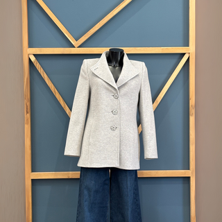 Gray coat on a mannequin against a geometric-patterned wall.