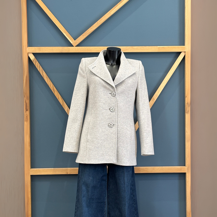 Gray coat on a mannequin against a geometric-patterned wall.