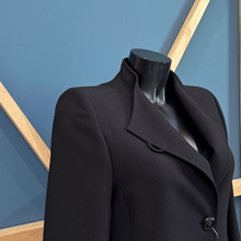 Load image into Gallery viewer, Black coat on a mannequin against a blue geometric background
